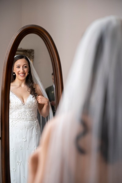 Bride looks at reflection in mirror smiling